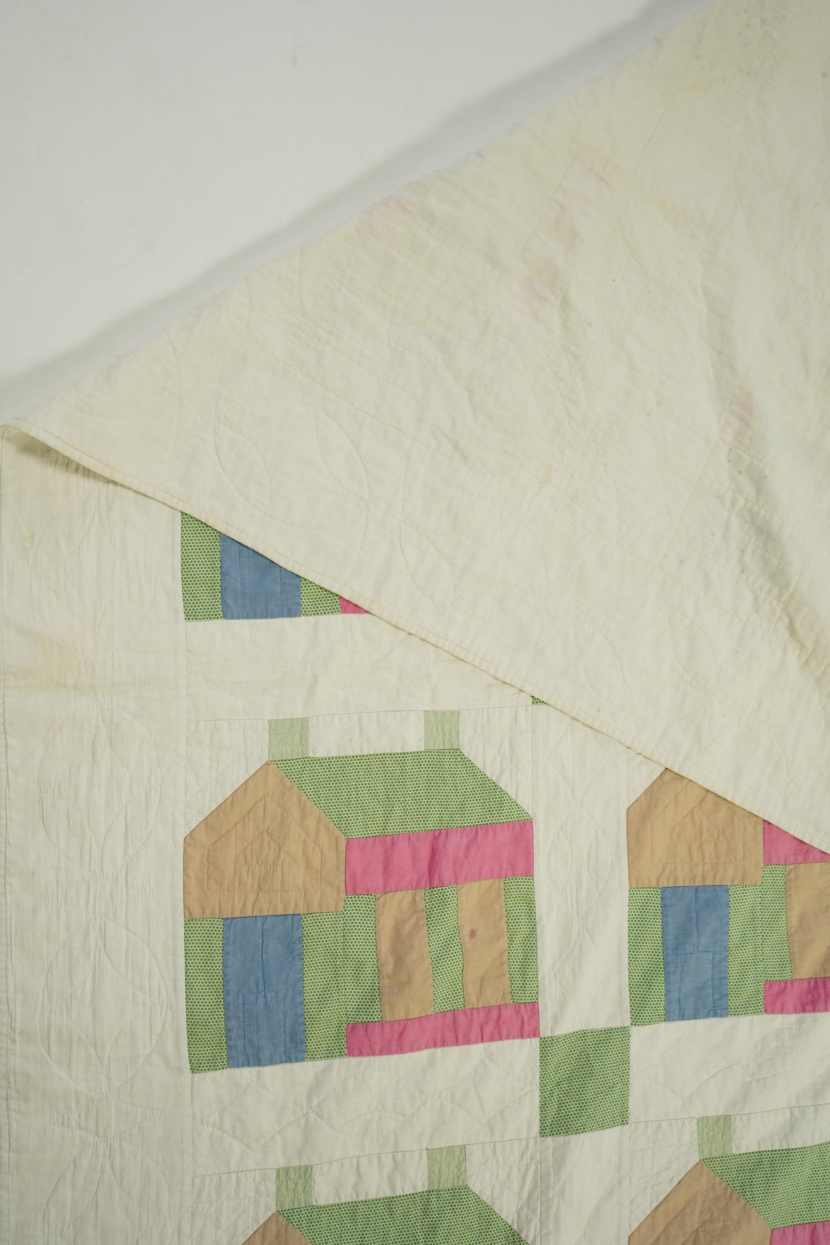 A 1930’s American quilt from Vermont. Quilted in large patchwork ‘house’ motifs, repeating the same four colours in each motif against a plain white background. The reverse a plain white quilted cotton . The quilt hand p